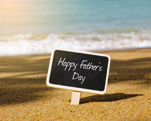 Happy Father's Day written on blackboard with blue ocean background.