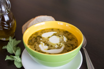 Potato and tarragon soup with cream on dark wooden background.