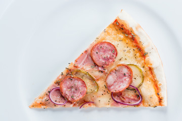 Slice of pizza with sausages, onions and pickles