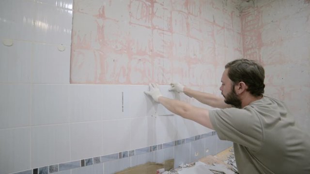 A worker of European appearance removes the old ceramic tile