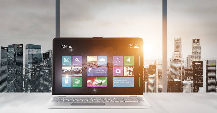 Laptop on table in office with panoramic sunset view of modern downtown skyscrapers at business district