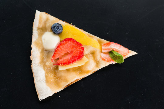 Piece of sweet pizza with strawberries on a dark background