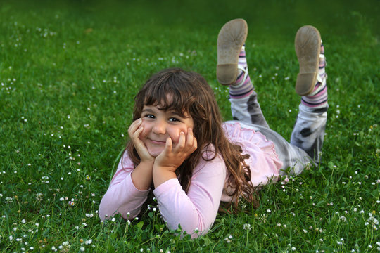 Kleines türkisches Mädchen lächelt, liegt entspannt auf der Wiese