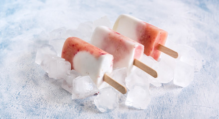 Healthy vegan coconut ice cream popsicles with peach White and red popsicles on melted ice