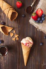 Ice-cream with fresh berries and chocolate sauce on the wooden background, top view