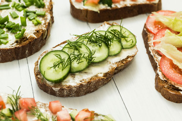 Assortment of vegetarian sandwiches with vegetables and cheese on a white table. Selective focus.