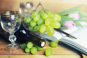 wooden table with wine bottle book and grape