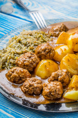 Homemade fried meatballs served with potatoes and cabbage.