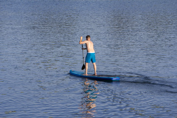 Man on Paddle Board paddling out to lake