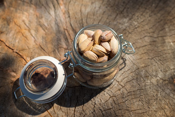 Fried peanuts in glass jar on wooden background