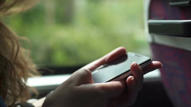Close up of female hand browsing photos on smartphone during bus ride