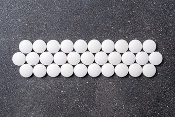 White pills on stone background. Close up