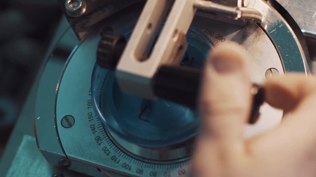Blue glass lens fastened in measuring machine with encrypted numbers disc at production facility, close up
