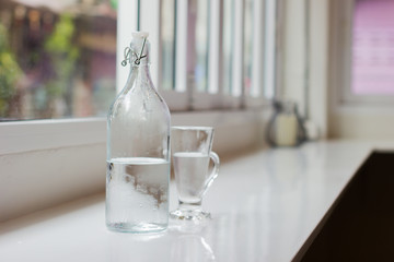 Glass of water with a bottle on table. Shallow depth of field. Horizontal photo