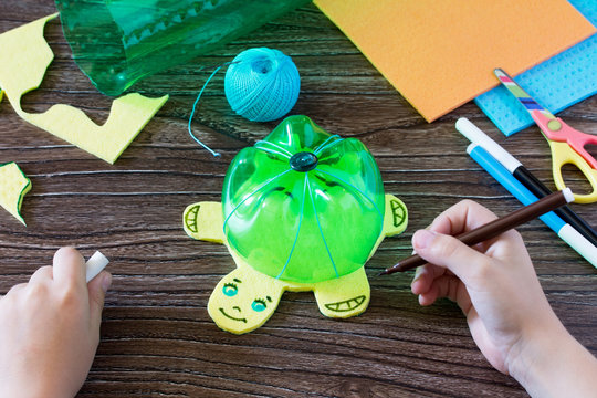 The child sews details of a children's hand-craft for money piggy bank. Handmade. Project of children's creativity, handicrafts, crafts for children.