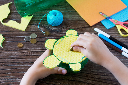 The child holds a children's hand-craft from a plastic bottle for money piggy bank. Handmade. Project of children's creativity, handicrafts, crafts for children.