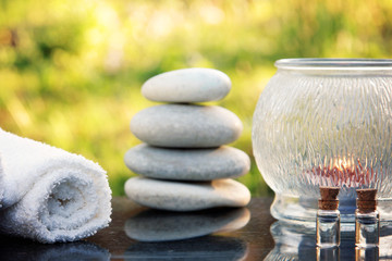 A spa treatment set, massage stones, a towel and massage oil are placed on a polished granite table...