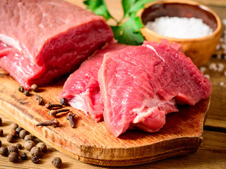Raw beef meat on rustic wooden cutting board.