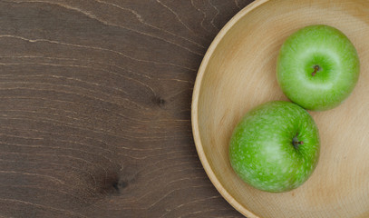 Two green apples in wooden bowl