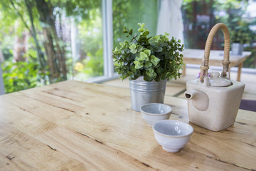 Japanese style teapot or kettle and teacup with small decorate tree on wooden table with Garden background
