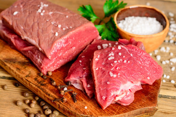 Raw beef meat on rustic wooden cutting board.
