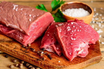Raw beef meat on rustic wooden cutting board.