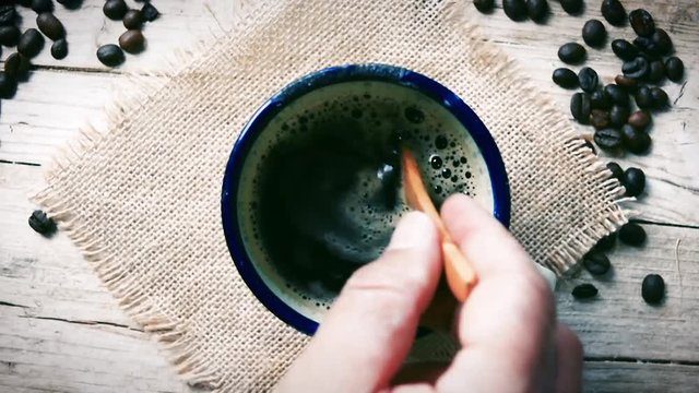 Man moves teaspoon into cup coffee