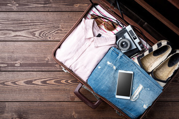 Open suitcase with casual female clothes on wooden table
