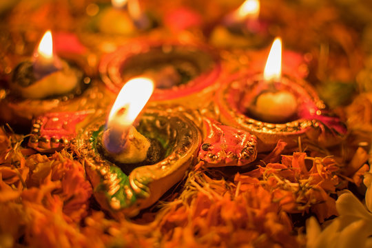 Very low angle view of Rangoli flowers and candles or diyas, Deepawali lights at night. Dark background stock image.