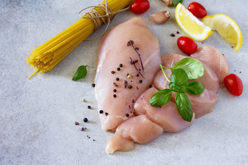 Fresh raw chicken fillet with spices and pasta on gray concrete, stone or slate. Food background....