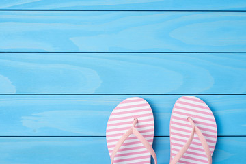 Pink flip flops on blue wooden background