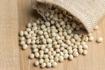 Soy bean in sack on wooden table