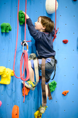Fototapeta premium little boy climbing a rock wall indoor
