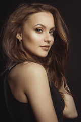 Naklejka premium Piękna brunetka dama w modnej czarnej sukni w studio