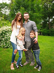 Young happy family with two children in summer green park