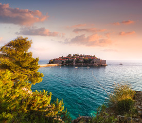 View in the Mediterranean sea and Sveti Stefan at sunset. Milocer Park. Coast Budva Riviera. Montenegro.