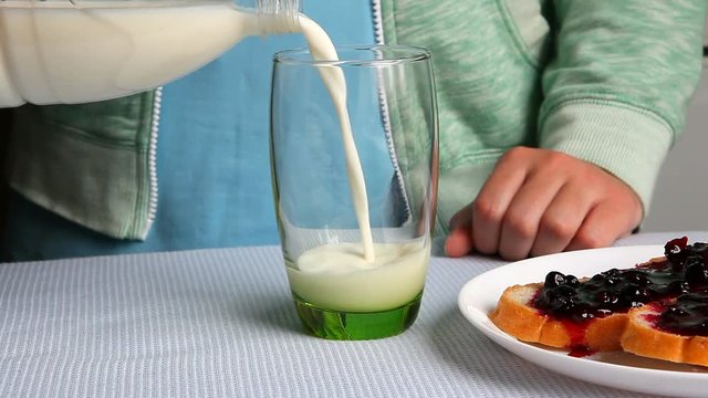 Woman pour milk in glass as breakfast concept