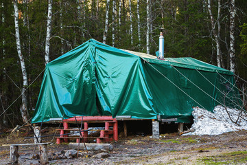 Green military tent with ladder at forest background as equipment for tourist camping.