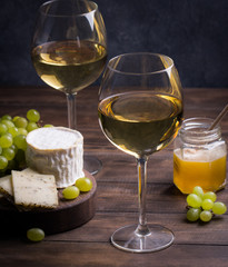 Various sorts of cheese, grapes and two glasses of the white wine