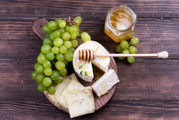 Various sorts of cheese, grapes and honey