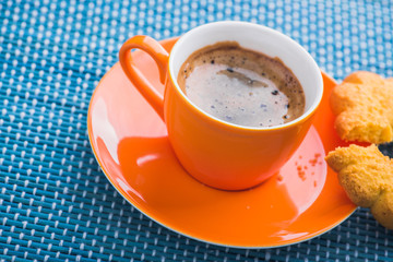 orange cup of coffee witt tasty cookie