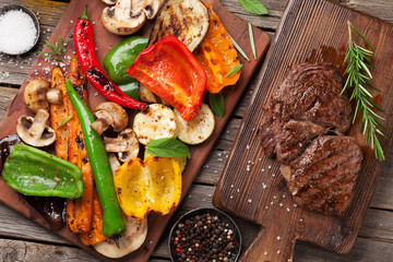 Grilled vegetables and beef steak on cutting board
