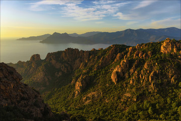 Landscape with mountains and sea at sunset,Corsica,France.Rocks lit by the sun against the sea.Rocks in the setting sun.