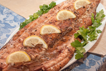 Still life of grilled red fish decorated with green parsley and lemon in a rustic style