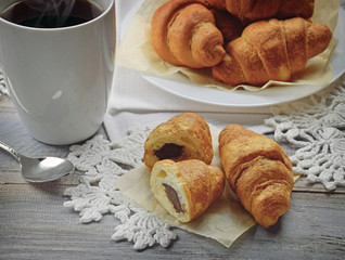 Hot drink and homemade croissants on an old wooden background.