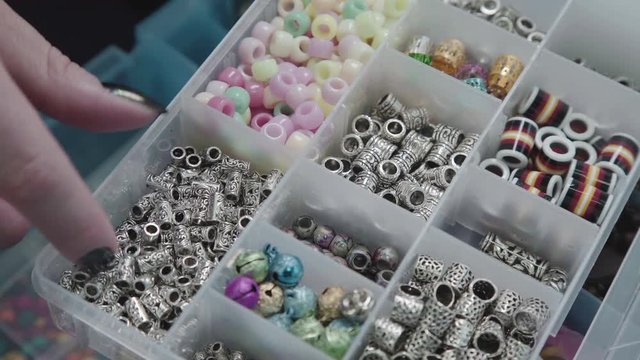 Accessories and fittings for decoration: beads, feathers, colored balls. The master selects the accessories for decoration. Accessories for creating ornaments and weaving braids.