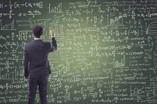 Portrait of businessman writing on blackboard