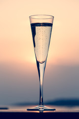 Glass of prosecco at a wooden pier at sunset. Luxury resort vacation concept. Festive relax getaway background.