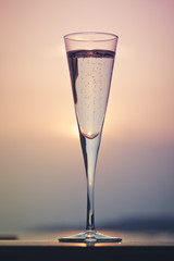 Glass of prosecco at a wooden pier at sunset. Luxury resort vacation concept. Festive relax getaway background.