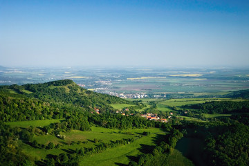 Fototapeta na wymiar Ceske Stredohori tourist area with hill Kamyk and Litomerice city on horizont and Kundratice village in foreground in spring evening czech landscape during sunset